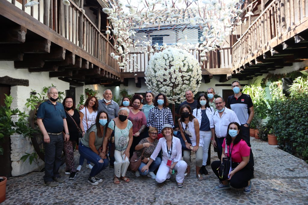 Group poses in a courtyard with flower decorations for the FLORA 2021 Festival in Córdoba