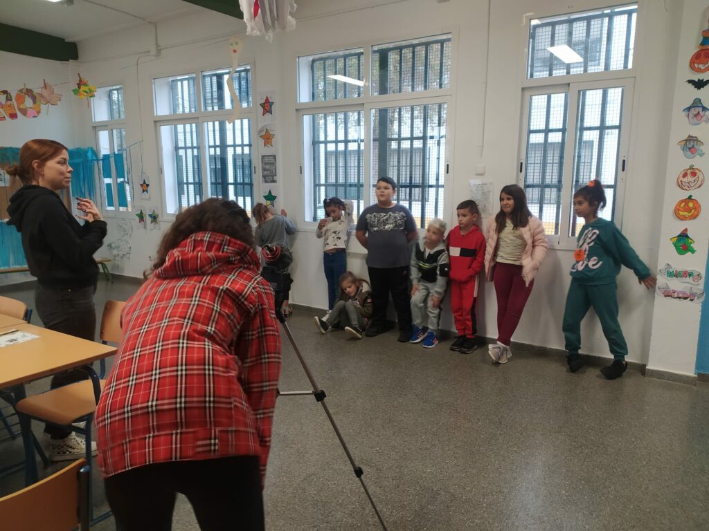 Kids in a classroom shooting a video with the help of adults. 